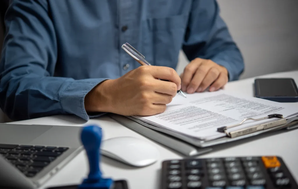 A compliance checklist with tax documents, a laptop, and a financial expert ensuring corporate tax adherence.

