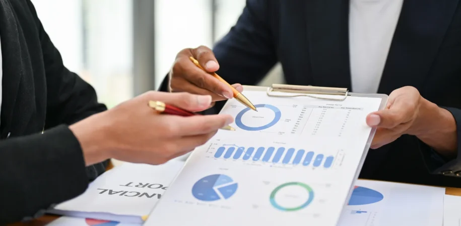 A financial expert analyzing project financing charts with graphs, documents, and investment reports on a desk.