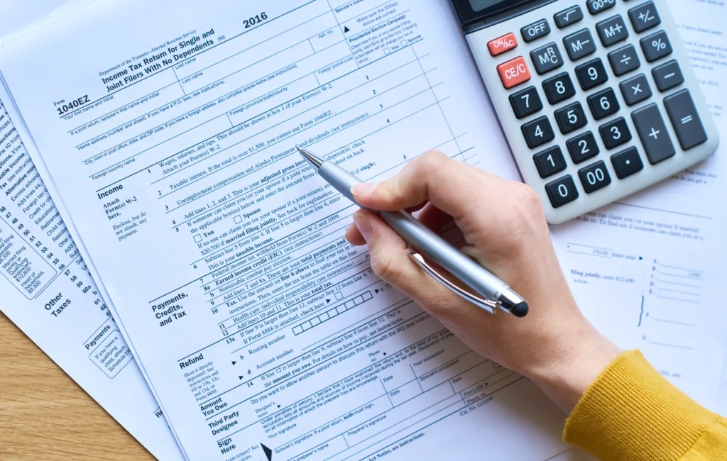 A business professional filing corporate tax returns online, reviewing financial documents on a laptop.